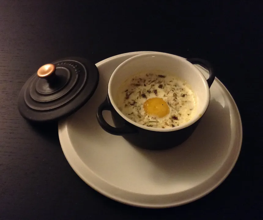 Œuf cocotte aux cèpes dans une petite cocotte noire, couvercle à côté